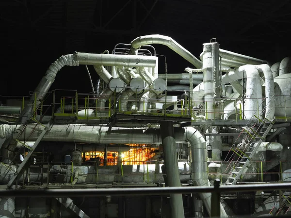 Pipes, steel tubes, steam turbine and equipment at industrial power plant, night scene