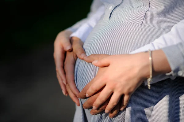 Gelukkig en jong zwangere paar knuffelen buiten — Stockfoto