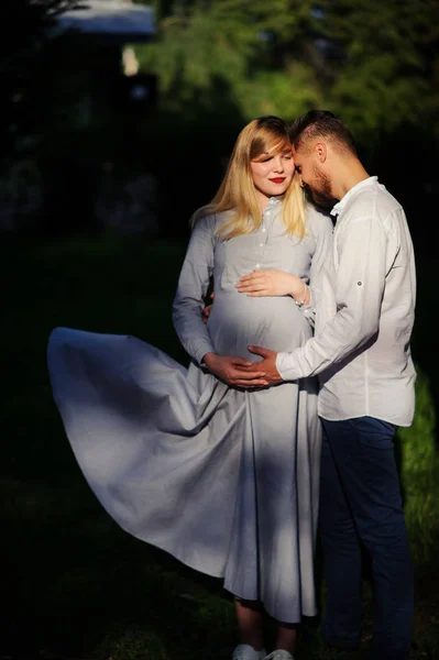 Счастливая и молодая беременная пара обнимается на открытом воздухе — стоковое фото