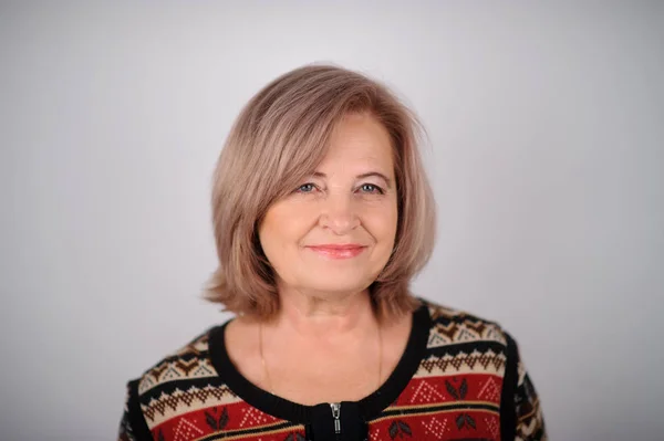 Porträtt av Senior Kvinna över grå bakgrund. Studio bild — Stockfoto