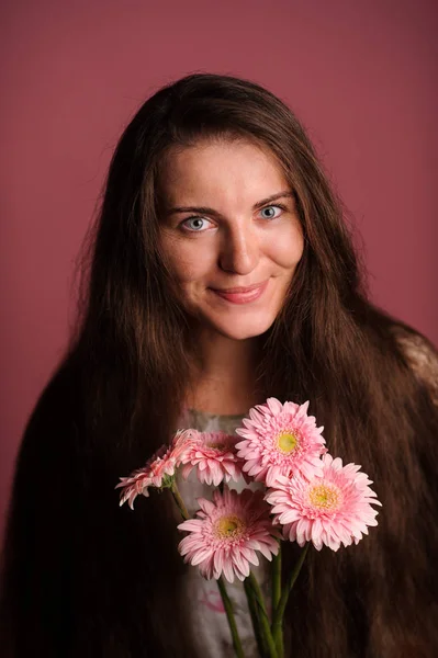 Mulher sorridente com flores cor de rosa. Estúdio fundo rosa — Fotografia de Stock