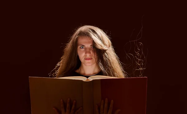 En magisk kvinne som leser en bok. svart bakgrunn – stockfoto