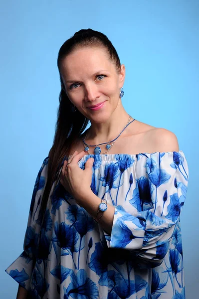 Porträt einer hübschen Frau in blauem Kleid vor blauem Hintergrund — Stockfoto
