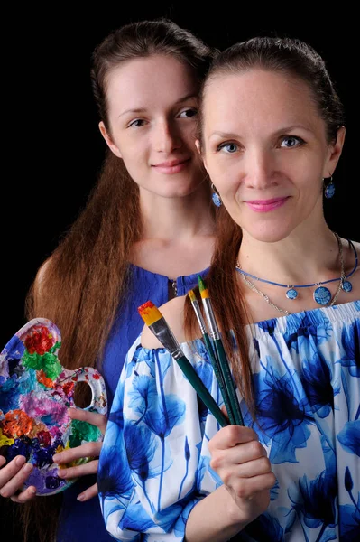 Two artists with paints and brushes in hands over black backgrou — Stock Photo, Image