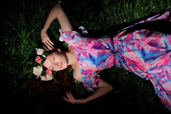 Young woman in wreath from folwers on a green grass — Stock Photo, Image