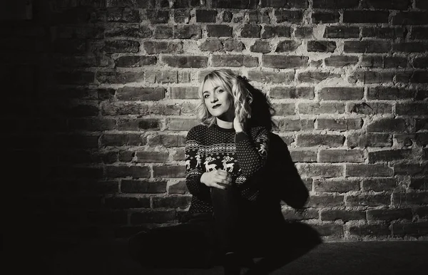 Молодая женщина в красном свитере возле кирпичной стены — стоковое фото