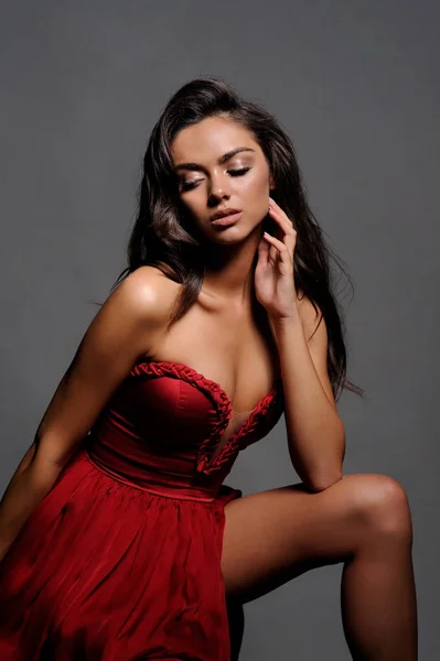 Prachtige vrouw in rode jurk. Studio foto, grijze achtergrond — Stockfoto