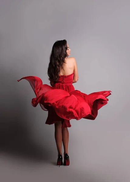 Wspaniała Kobieta w czerwonej sukni. Studio zdjęcie, szare tło — Zdjęcie stockowe