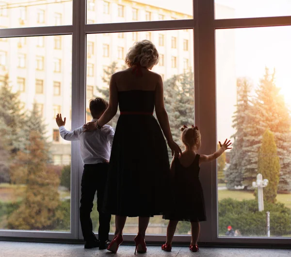 Gelukkige moeder met kinderen in de buurt van het raam — Stockfoto