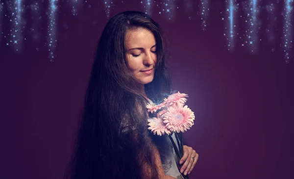 Leende kvinna med rosa blommor. Studio rosa bakgrund — Stockfoto