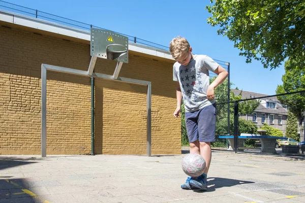 少年はストリートサッカーのピッチにボールを維持するために練習 — ストック写真