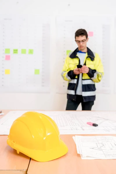 Yellow Helmet Blueprints Table Contractor Using Smartphone Office — Stock Photo, Image