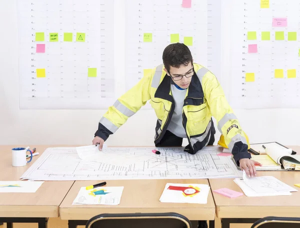 Trabalhador Construção Verificando Desenhos Design Escritório Usando Uma Jaqueta Segurança — Fotografia de Stock