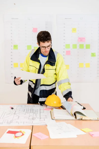 Joven Trabajador Construcción Pasando Páginas Mientras Sostiene Plano Oficina Imagen De Stock