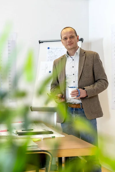 Senior Engineer Staande Naast Een Bureau Bezaaid Met Technische Tekeningen Rechtenvrije Stockfoto's