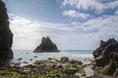 Uçurumlar ve kayalık kıyılar tarafından çerçevelenmiş İrlanda deniz yığını, bulutlu gün ortasında bulutlu gökyüzünün altında uzun süre açık kalan yumuşak su.