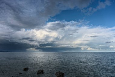 Klasik İrlanda deniz manzarası dalgalı su, ağır bulutlar parlak mavi gökyüzü, ve ince uzak kıyı şeridi.