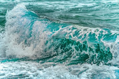 İrlanda kıyılarında güçlü turkuaz dalgalar, beyaz köpük ve hareket halinde sprey, düşük açılı yatay deniz manzarası.