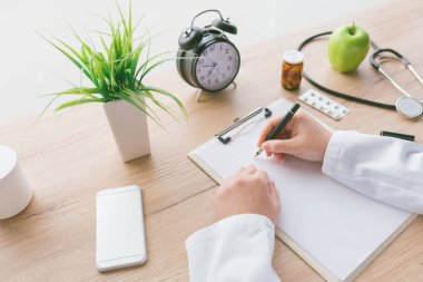 Kadın doktor hastane ofisinde muayene sırasında Notlar, hastanın tıbbi geçmişini veya ilaç reçete Pano kağıda yazı