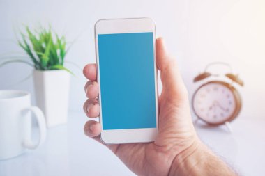 Sabah, boş ekran cep telefonuyla kopya alanı ofis olarak tutan erkek el kahve molası sırasında Smartphone kullanarak
