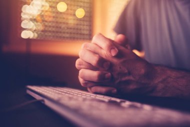 Bilgisayar klavye üzerinde dua. Erkek ellerini sıktı veya ev ofis iç, düşük anahtar seçici odak ile bulunduğu dua etmenin sıktı
