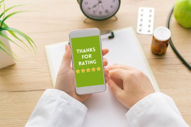 Kadın doktor elinde smartphone ekranda derecelendirme iletisi için teşekkür ederiz. Hastalar ve müşteri servisi anket geri bildirim kavramı.