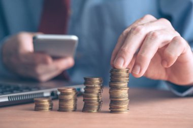 Smartphone ile kullanarak işadamı paralar ön planda yığılmış, seçici odak ile atış kadar yakın