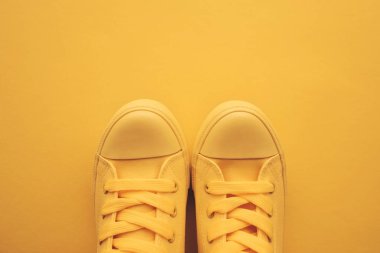 Spor ayakkabı ayakkabı gençlik yaşam tarzı konsepti için pastel tonda sarı ayakkabı ile kopya alanı, üstten görünüm