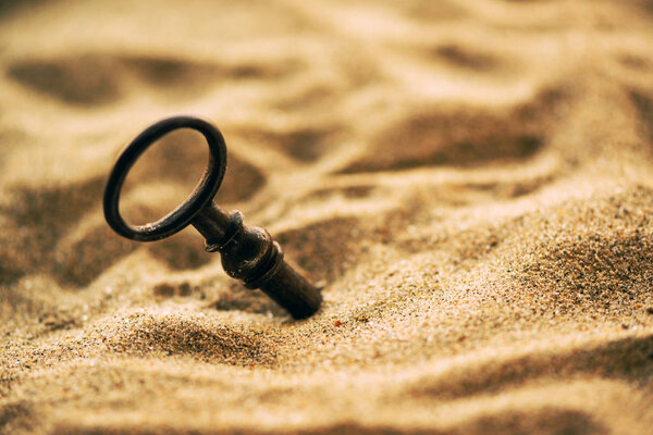 Old lost key in the sand is a newly found opportunity