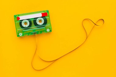 Top view of audio cassette with tangled tape on bright yellow background with copy space, minimalistic composition clipart