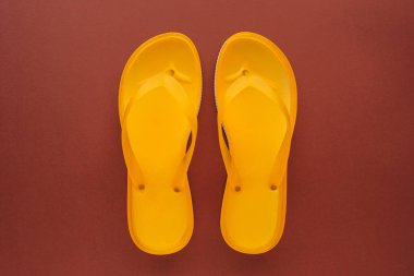 Sarı beach flip flop üzerinde kahverengi zemin, üstten görünüm