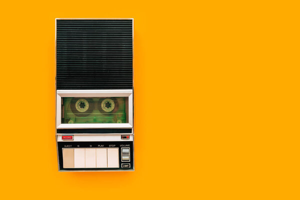 Top view of audio cassette tape player on bright yellow background with copy space, minimalistic retro style composition