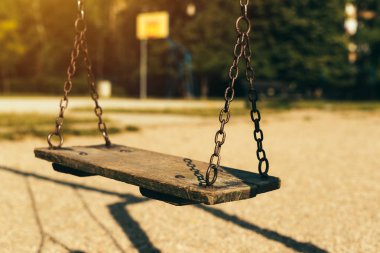 Old abandoned swing on children's playground in the morning clipart