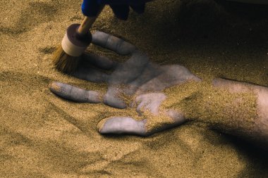 Forensic expert discovering dead body buried in desert sand. Conceptual image for police investigation of an cold case murder crime scene. clipart