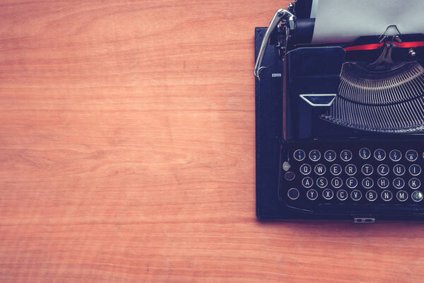 Vintage typewriter machine on writers desk, top view flat lay conceptual image for blogging, publishing, journalism or poetry writing.