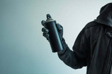 Yaklaşık boş duvara sokak bazı sanat eseri yaratmak için renk sprey can tutan grafiti sanatçısı