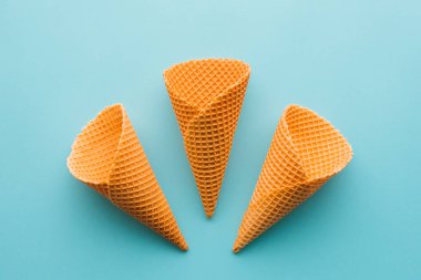 Pastel mavi zemin üzerine üç dondurma koni yukarıdan en az düz kompozisyon kopya alanı ile yatıyordu.