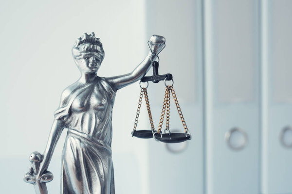 Lady Justice statue with document ring binders in law office