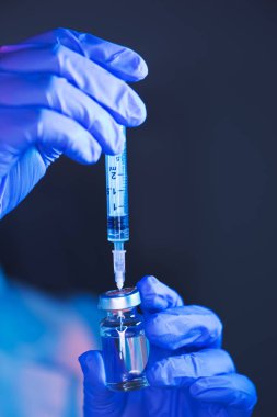 Doktor aşı şişesinden solüsyon hazırlıyor ve hasta aşısı için tıbbi klinikte şırınga dolduruyor.