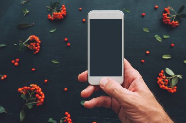 Smartphone ekran sahte çiçek düzenleme ile koyu arka plan üzerinde kullanarak ele