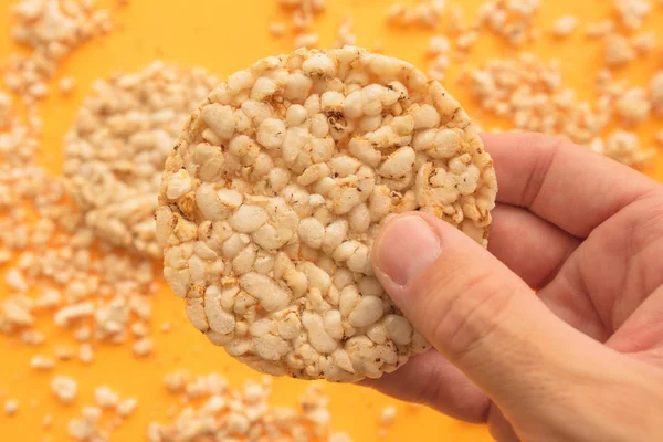 Reiskuchen Männerhand Vor Gelbem Hintergrund Overhead Ansicht — Stockfoto