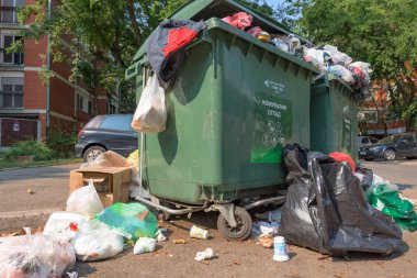 NOVI SAD, SERBIA - AUGUST 18, 2018: Municipal solid waste or communal garbage is overflowing containers in Novi Sad during weekends, illustrative editorial clipart