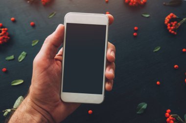 Smartphone ekran sahte çiçek düzenleme ile koyu arka plan üzerinde kullanarak ele