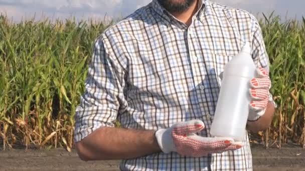 農家の畑で農薬化学ボトルを保持しています 除草剤 コピー領域をモックとして空白のラベルのないプラスチック容器殺菌剤や殺虫剤トウモロコシに使用される作物の農業 — ストック動画