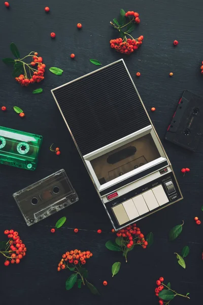 Flat lay music audio cassette and player, nostalgic image top view of retro technology from 80s and 90s with wild berry fruit decoration arrangement