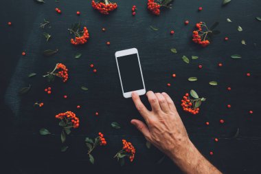 Düz yatıyordu el Smartphone ekran sahte çiçek düzenleme ile koyu arka plan üzerinde kullanma