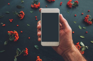 Smartphone ekran sahte çiçek düzenleme ile koyu arka plan üzerinde kullanarak ele