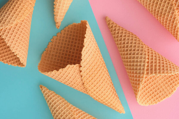 Ice cream waffle cones on pastel pink and blue background, top view flat lay modern minimal composition