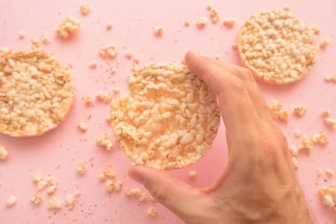 Pastel pembe bir arka plan üzerinde havai görünümü pirinç kek erkek el