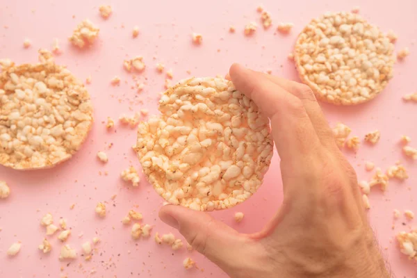 Reiskuchen Männlicher Hand Über Pastellrosa Hintergrund Overhead Ansicht — Stockfoto